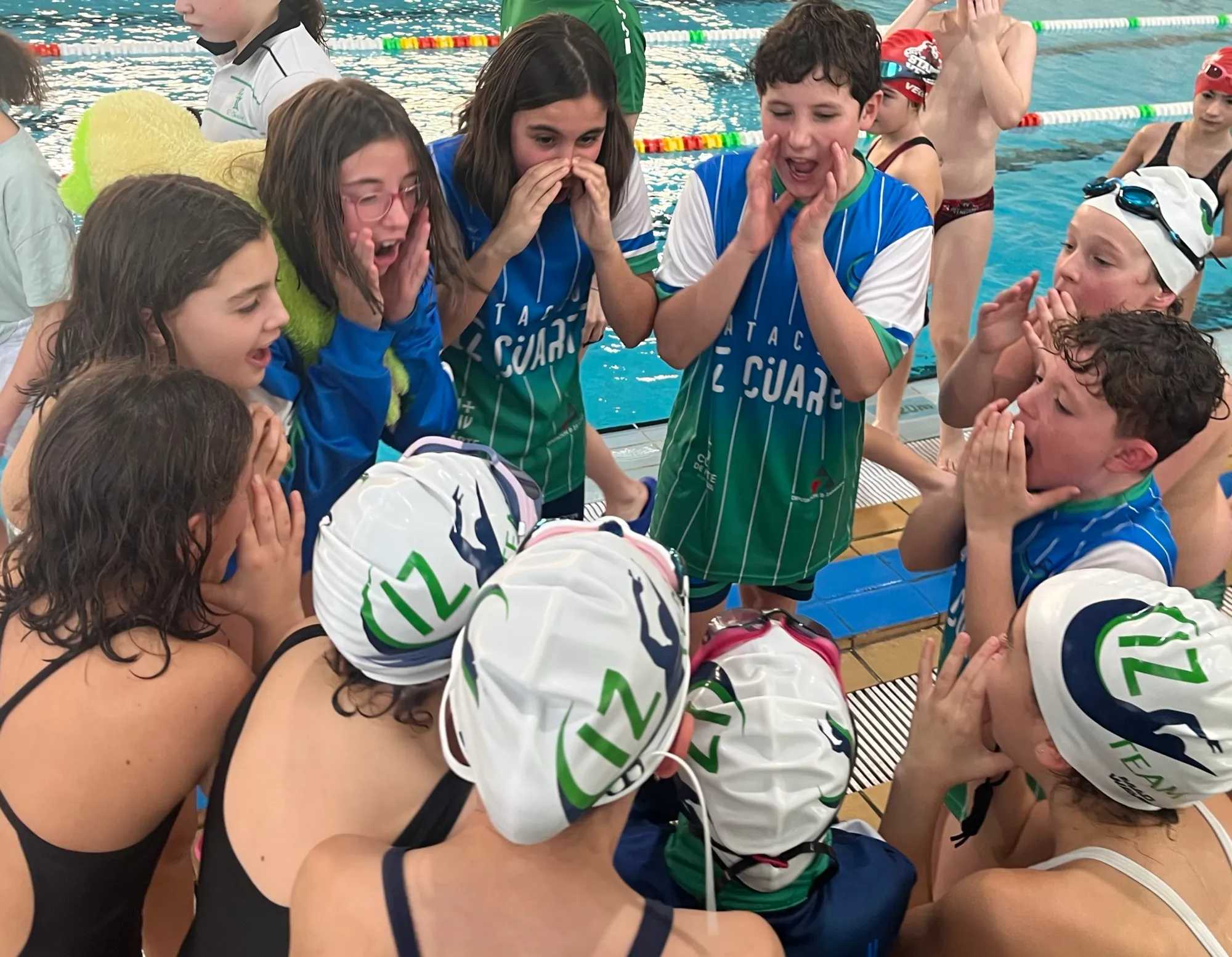 Equipo del club reunido junto a la piscina, animándose en corro.