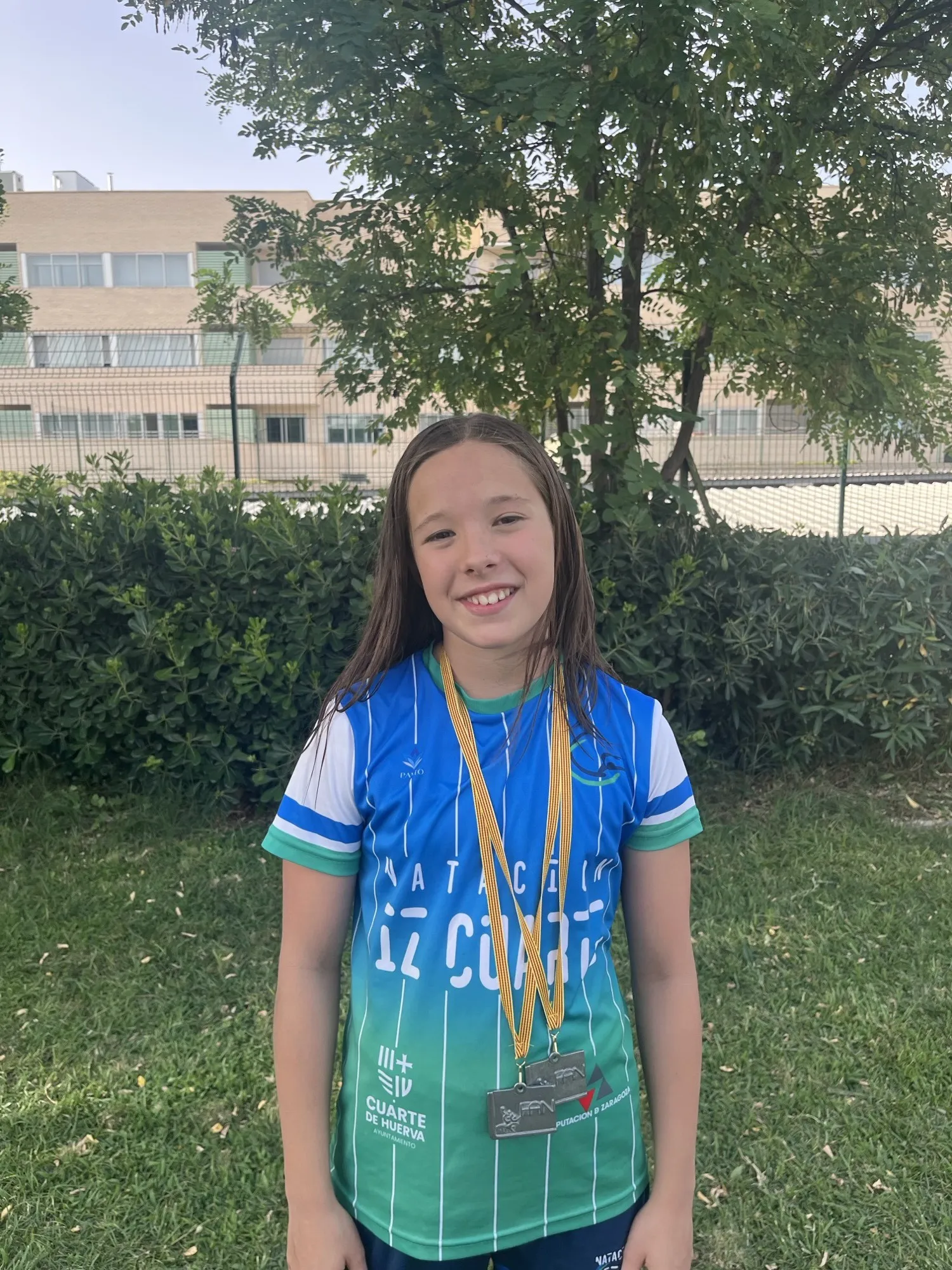 Vega Moreno, nadadora alevín del Club Natación IZ Cuarte, sonriente y con la equipación del club, luciendo las dos medallas conseguidas en el Campeonato de Aragón