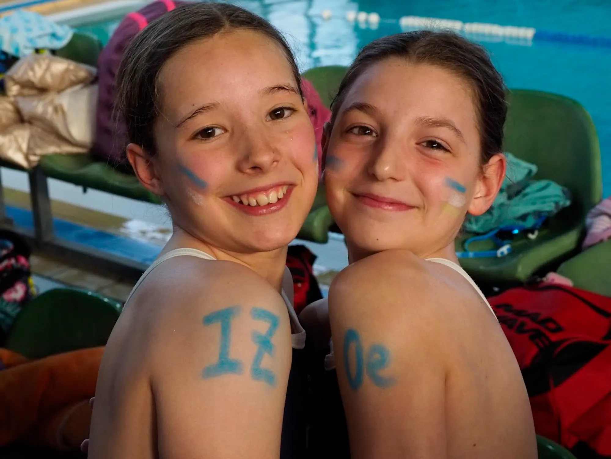 Dos nadadoras del club sonriendo junto a la piscina.