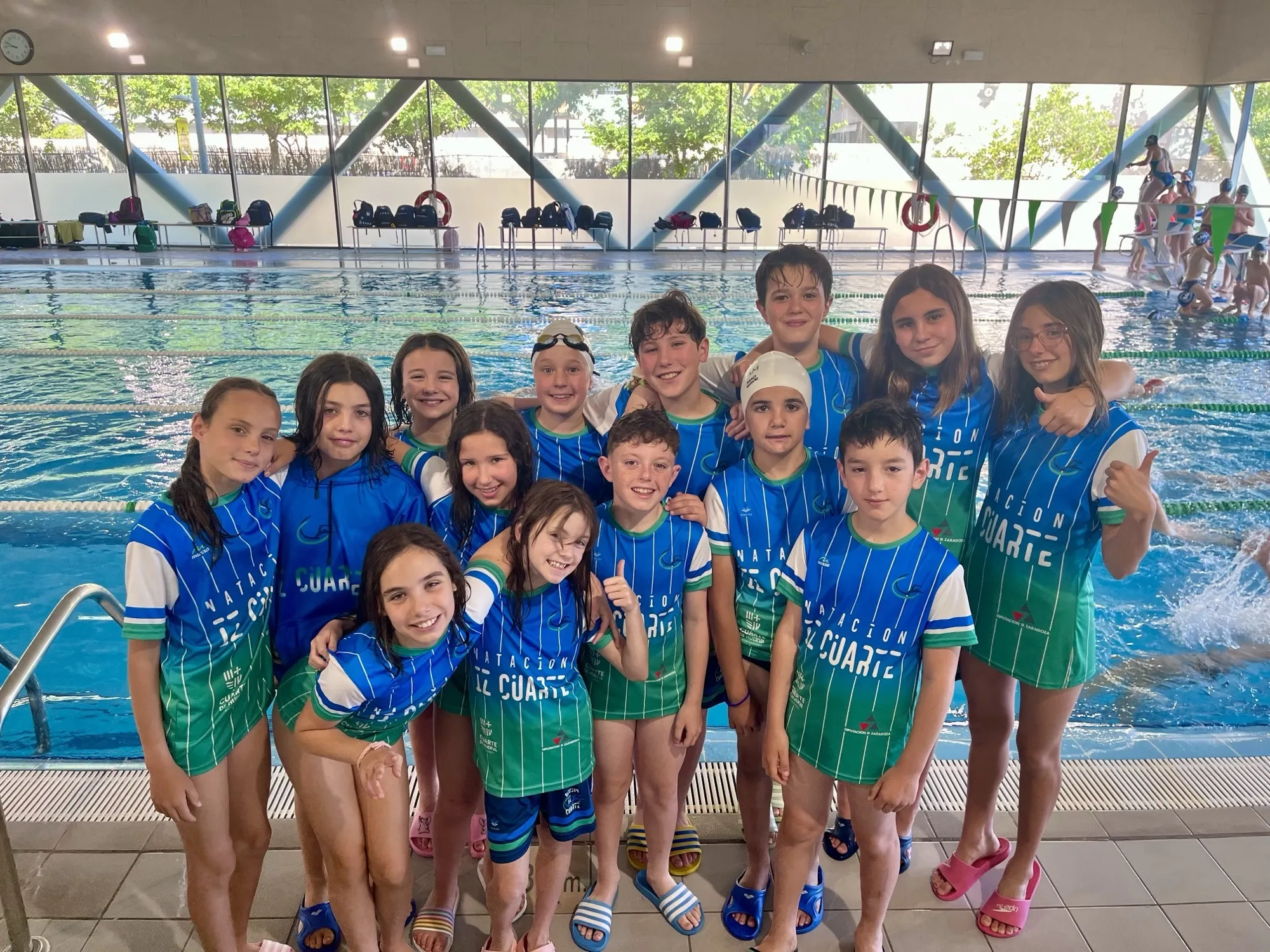 Equipo benjamín del Club Natación IZ Cuarte posando junto a la piscina
